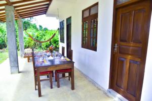 a wooden table with chairs and a wooden door at Maiya Wild Ship Villa in Kosgoda