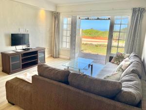 a living room with a couch and a tv at 8 Settler Sands Ocean View in Port Alfred