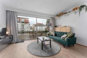 a living room with a green couch and a table at Lilyta B201 in De Haan