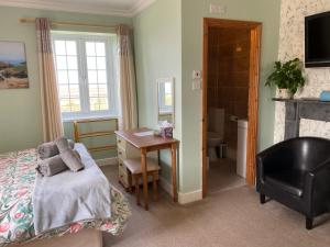 a bedroom with a bed and a desk and a chair at Haelarcher Farmhouse and Helicopter B&B in Lizard