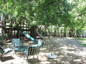 a playground with a slide and chairs under a tree at The Barn On 62 - Cottages in Montagu
