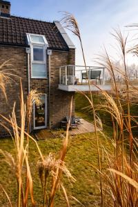 a brick house with a balcony and grass at Apartament Vespa in Mechelinki