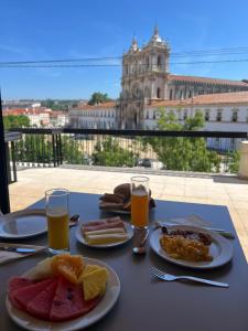 a table with plates of food and glasses of orange juice at Hotel Santa Maria in Alcobaça