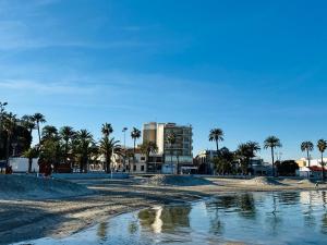a view of a beach with palm trees and a building at Albohera Playa hotel by Belvilla Resorts in Santiago de la Ribera