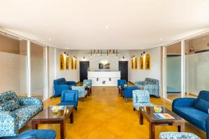 a waiting room with blue chairs and tables at Sterling Kanha in Kānha