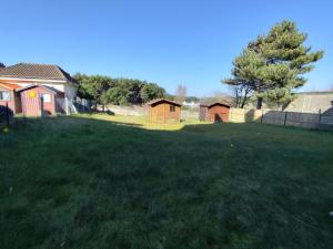 a grassy yard with a house and a fence at Yvéro in Quend-Plage