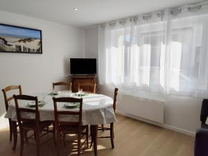 a dining room with a table and chairs and a television at Yvéro in Quend-Plage