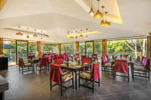 a dining room with tables and chairs and windows at Sterling Kanha in Kānha