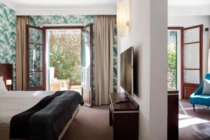 a hotel room with a bed and a tv and a chair at Hotel Esplendido in Port de Soller
