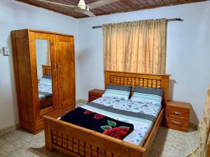 a bedroom with a wooden bed and a mirror at Home & Heart Gambia in Brusubi