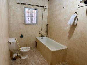 a bathroom with a tub and a toilet and a window at Home & Heart Gambia in Brusubi +12 photos