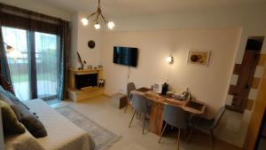 a living room with a desk with chairs and a television at SiviriLovelyApartment in Siviri