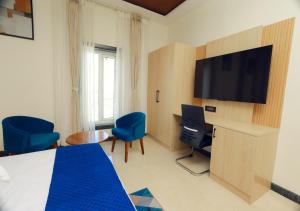 a hotel room with a bed and a flat screen tv at Vitash Inn in Tirupati
