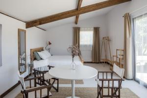 a room with a white bed and a table and chairs at As Casas Do BomPai - Eira in São Julião