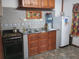 a kitchen with a sink and a stove and a refrigerator at Cabaña Óga Pora' in Puerto Yeruá