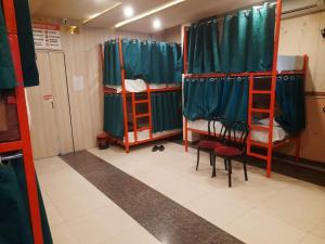 a room with three bunk beds and two chairs at Cozy bunks z hostel in Dehradun