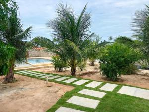 a garden with palm trees and a swimming pool at Apart hotel Refúgio tropical Icarai de amontada in Amontada