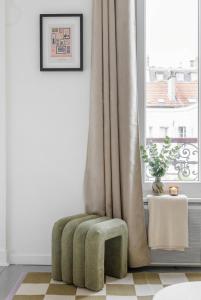 a green stool sitting in front of a window at FurtiveStay - Les Sablons - Orléans in Neuilly-sur-Seine