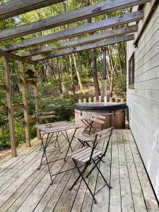 eine Terrasse mit Tisch und Stühlen auf einem Holzdeck in der Unterkunft Tiny de Paula in Saint-Hubert