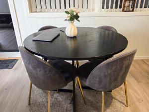 a black table with chairs and a vase with flowers at GHAR-New 2 bedrooms apartment near airport and Oslo city-free parking in Klofta