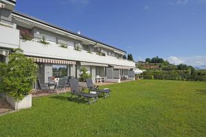 a building with chairs and tables on a lawn at Petronella - Gardagate in Soiano del Lago