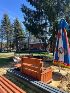 a park with benches and an umbrella and a table at Przyczepa BOHO in Ciężkowice +8 photos