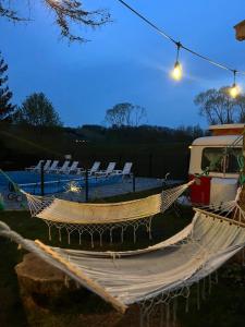 a hammock in a yard with chairs and a boat at Przyczepa BOHO in Ciężkowice