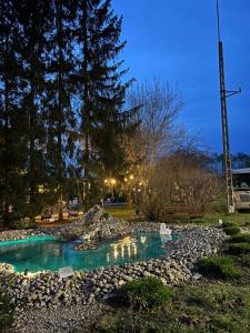 a small pond with rocks in a park at night at Przyczepa BOHO in Ciężkowice