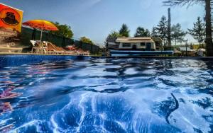 a swimming pool with an rv in the background at Przyczepa BOHO in Ciężkowice