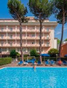 a woman in a swimming pool in front of a hotel at Hotel Tiffany in Rimini