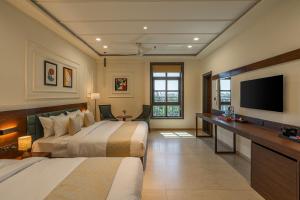 a hotel room with two beds and a flat screen tv at Perfectstayz premium stepwell by the lake in Udaipur