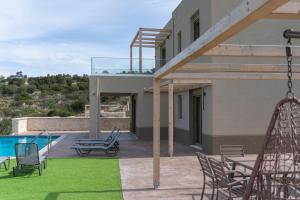 a patio with chairs and a swing next to a house at Amnia Villas with Private Pool in Kapsalianá
