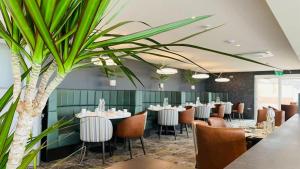 a restaurant with tables and chairs and a palm tree at The Cliff Hotel & Spa in Cardigan