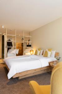 a large bedroom with a large white bed and a yellow chair at Posthotel Alexander Herrmann in Wirsberg +25 photos
