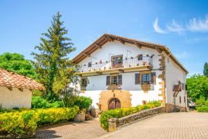 a white house with a balcony and a tree at Casa Arozenia, Hogar rústico en pleno valle Ulzama in Lizaso +39 photos
