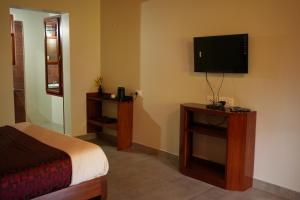 a bedroom with a bed and a flat screen tv at Deva Maani Coorg Nature View in Madikeri
