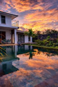 a house with a pool in front of a sunset at Vanilla Lodge Tropical Garden Suite with Outdoor Stone Bath & Bamboo Shower, inifinity pool in Cap Malheureux