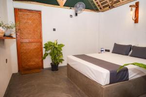 a bedroom with a bed and a plant and a door at Villa Carlos Tangalle in Tangalle