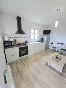 a white kitchen with a stove and a table at Les 3 métisses-lyia in Le Bugue
