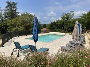 a swimming pool with chairs and umbrellas in a yard at Les 3 métisses-lyia in Le Bugue