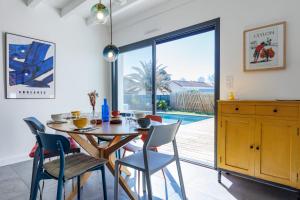 a dining room with a wooden table and chairs at Villa Blue Pool - Welkeys in Seignosse