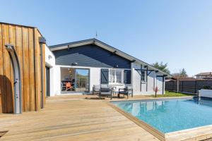 a house with a swimming pool and a wooden deck at Villa Blue Pool - Welkeys in Seignosse