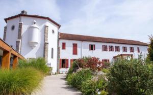 a white building with red shuttered windows and a pathway at Anetania in Saint-Palais
