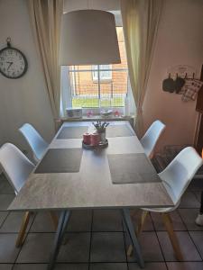 a dining room table with white chairs and a clock at Design Wohnung in Petersdorf auf Fehmarn