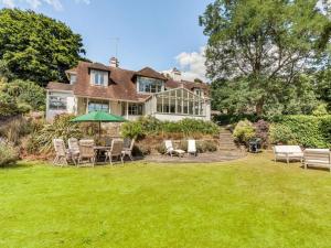 a house with chairs and an umbrella in the yard at 4 Bed in Pulborough oc-89346 in Fittleworth