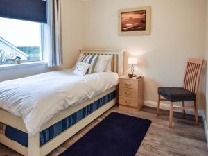 a bedroom with a bed and a chair and a window at 2 Bed in Helston oc-54556 in Mullion