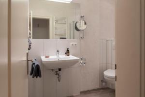 a white bathroom with a sink and a toilet at Posthotel Alexander Herrmann in Wirsberg