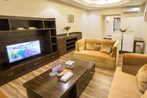 a living room with a television and a couch and a table at White Moon Al Sadd in Doha