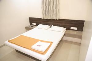 a bedroom with a white bed with a wooden headboard at Hotel Maharaja in Thane +38 photos