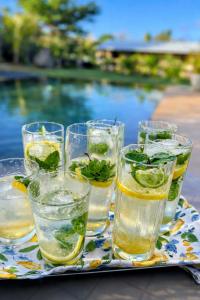 a tray with several glasses of water and a pool at Cinnamon Room Four-Poster Bed, Freestanding Bath, Walk-In Shower & Infinity Pool in Cap Malheureux